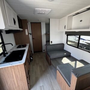 Modern camper interior with kitchen and seating.