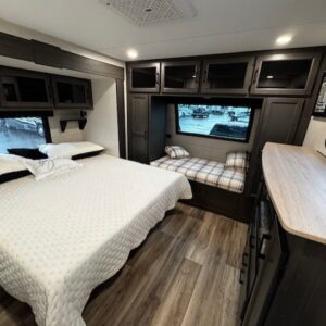 Camper bedroom with bed and small window.