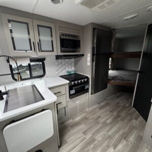 Modern RV kitchen with bunk beds.