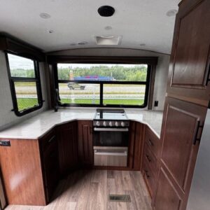 RV kitchen with stove and large windows.