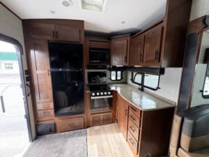 RV kitchen with wooden cabinets and appliances.
