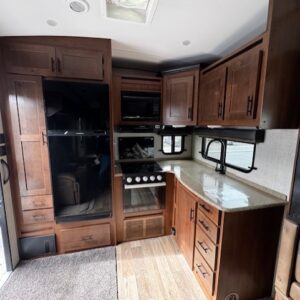 RV kitchen with wooden cabinets and appliances.
