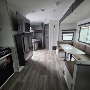 Interior view of a modern RV with kitchen and dining area.