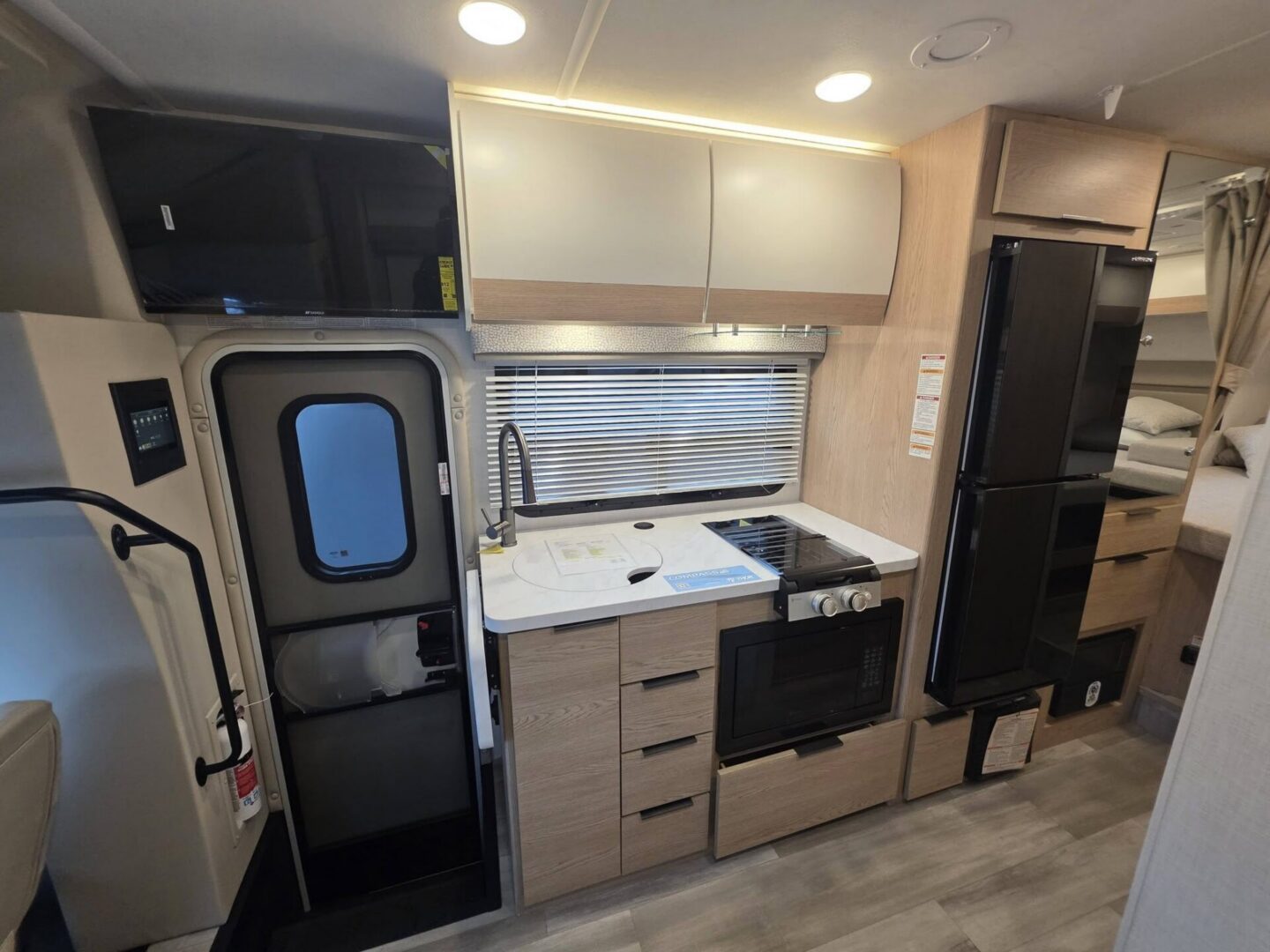 Modern camper kitchen with appliances and storage.