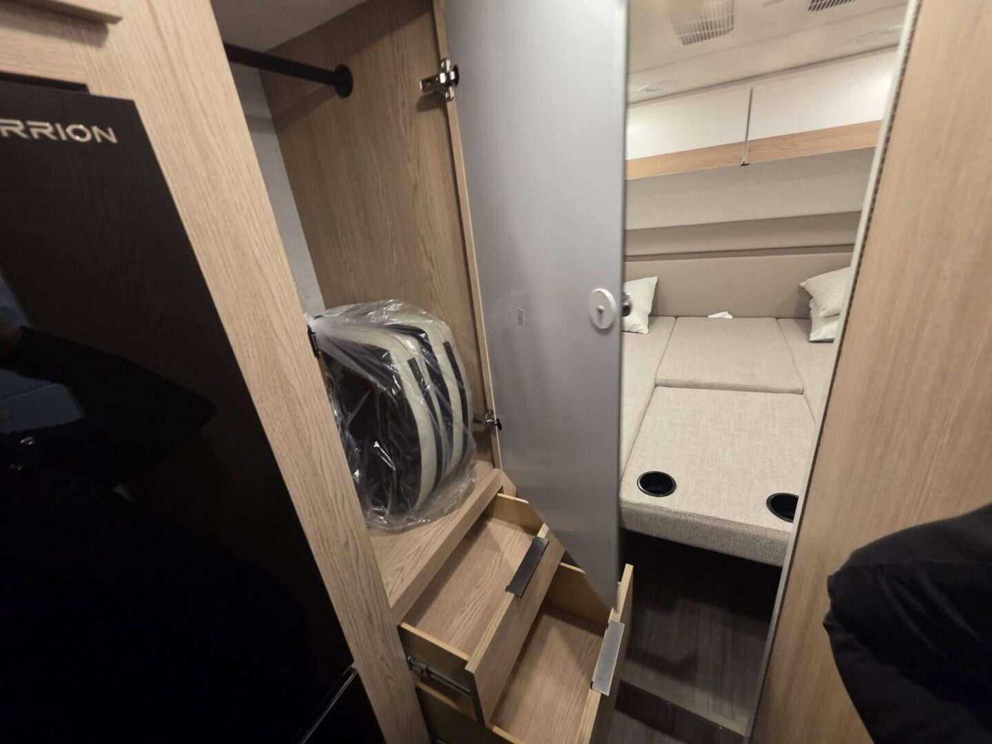 Compact camper interior with bed and storage.