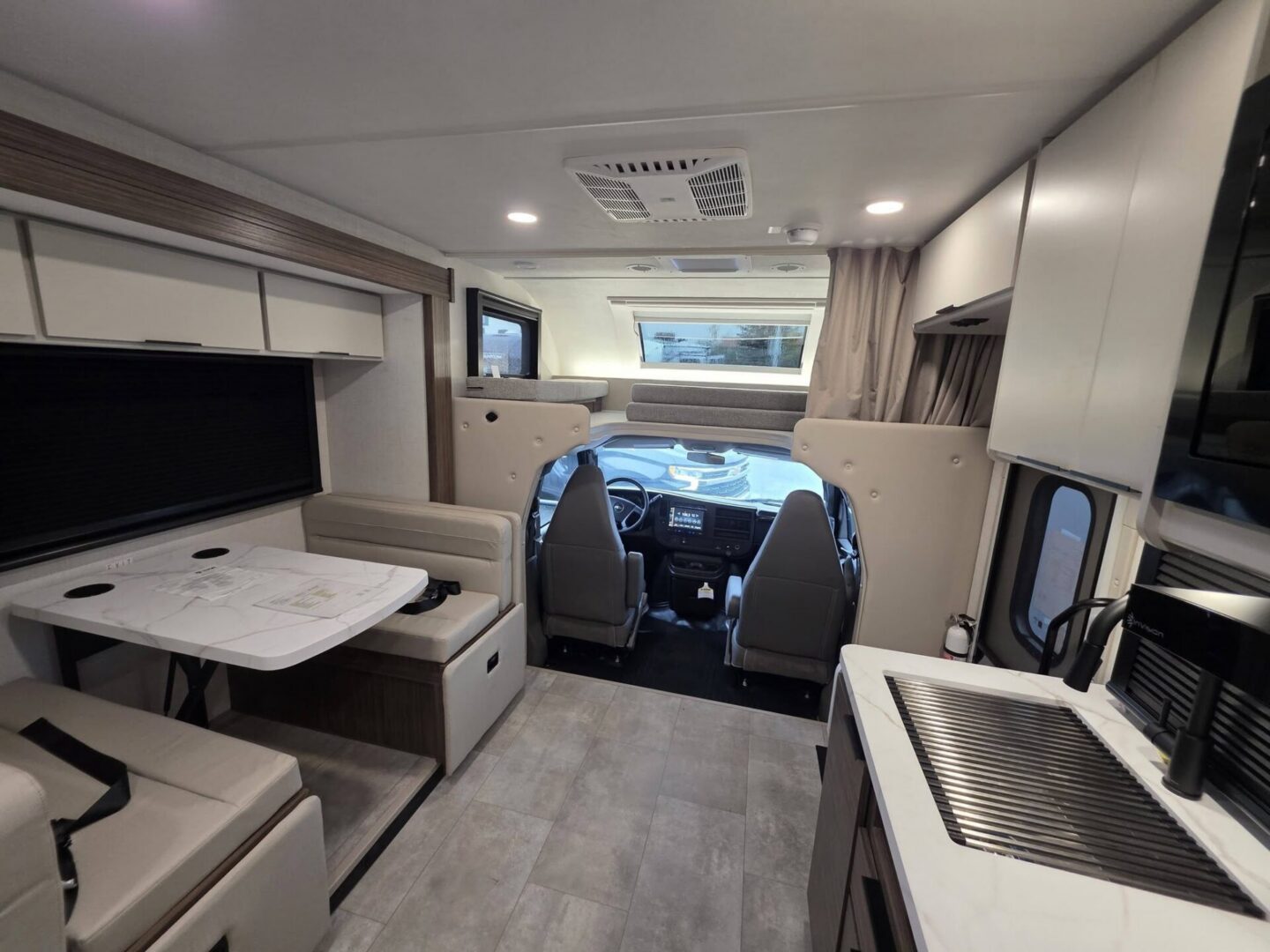 "Modern RV interior with dining and driving areas."