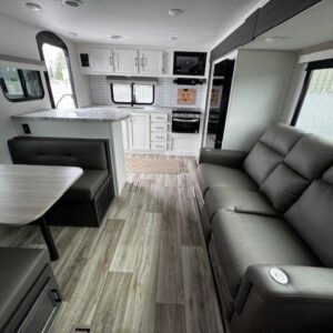 Modern RV interior with seating and dining area.
